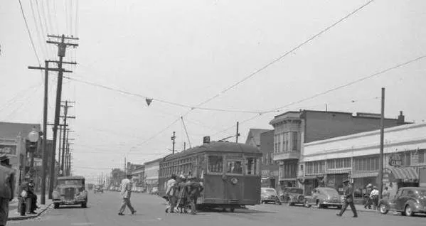 West Oakland 7th Street before freeway construction, pre-1955 — streetcar, pedestrians, thriving Black commercial corridor known as the Harlem of the West